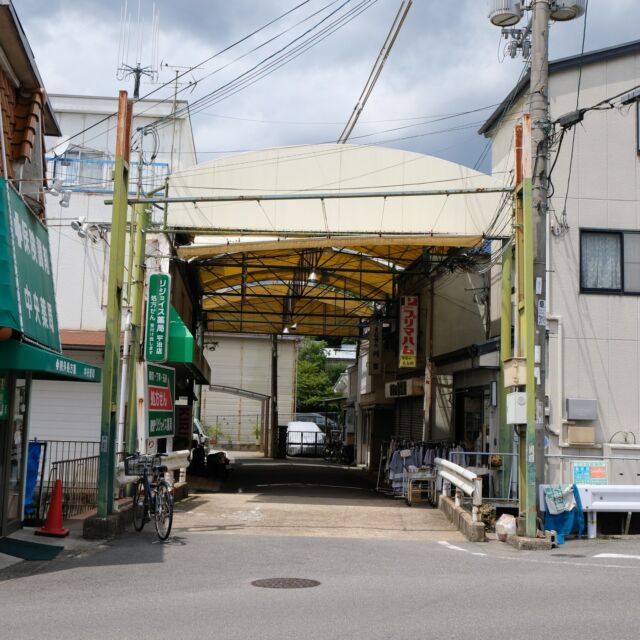 京都府は宇治市、京阪もしくはJRの黄檗（おうばく）駅から北へ数百メートルほど行くと見えてくるのは「南端ショッピングプラザ」。

総延長25mほど、営業している店舗はわずか3件ほどの日本一短い（!?）商店街です。

これは間に合ったのか、いや間に合わなかったのか・・・看板部分が取り外された「アーチだったもの」の骨組みだけが残っておりました。

ストリートビューで見ると2018年時点では看板の両面がありましたが、2020年には表側が外れ、そしてついに両側がなくなってしまったようです。これも撤去が近そうです。

ところで「南端」って地名は何の南側なのかと思って検索してみたのですが、目ぼしい情報はなし。

周辺を見てみると小字に「南山」「南山畑」「北山畑」なとど山や畑を表す地名が並ぶので、「端」というのは国語辞典で「山なみの中で人里近い低山。端近い小山。」を表す「端山」のことなのかと推測しました。

北山畑と南山畑や南端の間には皇族や藤原氏の墓所である「宇治陵」の総遥拝所があり、さらにその西側は「西浦」という地区がありますので、「南端」は宇治陵の南の端山、ということなのでしょうかね。

もし間違っているようでしたらご一報くださいませ。

Entrance arch of Nantan shpooing plaza at Uji city, Kyoto, Japan.
2022
#アーチ看板 #アーチ #商店街 #商店街ゲート #街歩き #京都府 #宇治市 #黄檗 #南端ショッピングプラザ #arch #street #japan_photo #japan #Kyoto #Uji #Obaku #日本一 #ノスタルジー #間に合わなかった #地名 #宇治陵